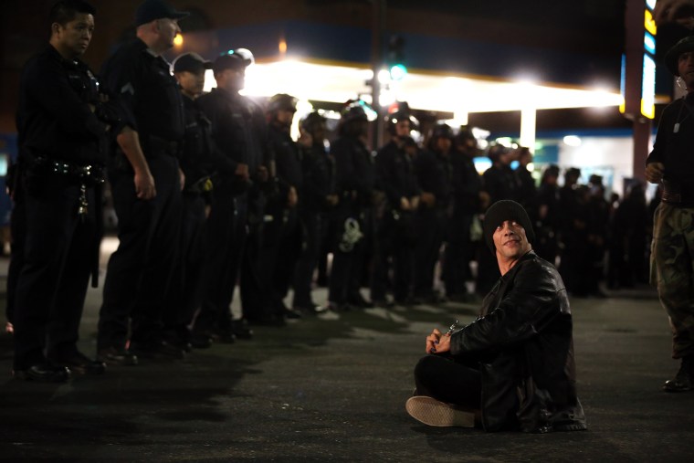 Victor Licata sits in front of Oakland police officers during a protest against Mayor Libby Schaaf's curfew policy in Oakland, Calif., June 5, 2015. (Photo by Ray Chavez/Bay Area News Group/AP)