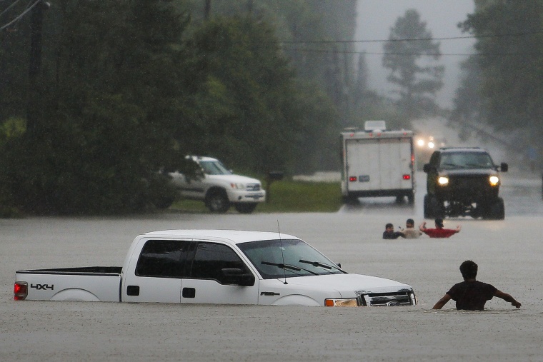 Three men, pictured in the background, lost control of their truck after they drove around a closed road barrier along Nichols Sawmill Road in rising flood water, May 27, 2016 in Magnolia, Texas. (Photo by Michael Ciaglo/Houston Chronicle/AP)