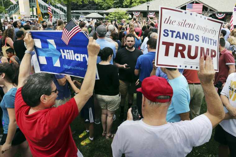A supporter of Democratic presidential candidate Hillary Clinton and a Republican presidential candidate Donald Trump supporter hold signs as they attend a Memorial Day parade on May 30, 2016, in Chappaqua, N.Y. (Photo by Mel Evans/AP)