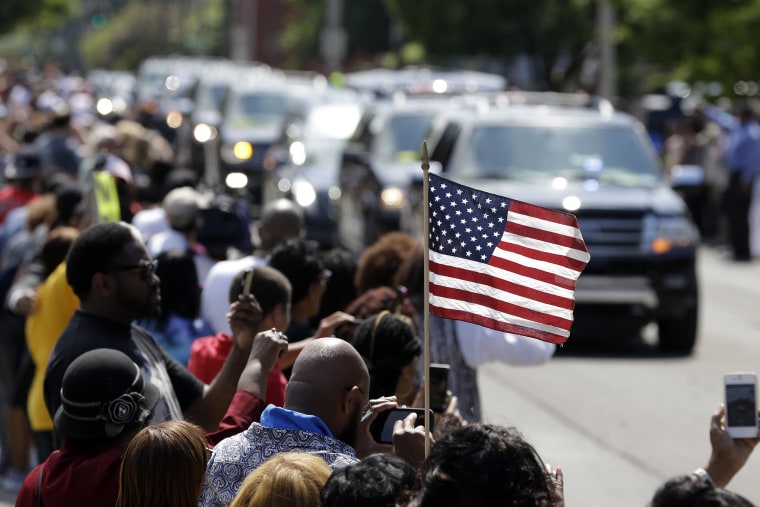 A mourner holds an American flag as the funeral procession for Muhammad Ali makes its way down Muhammad Ali Boulevard in Louisville, Ky. on June 10, 2016. (Photo by Michael Conroy/AP)