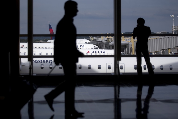 The silhouettes of a travelers are seen walking past Delta Air Lines airplanes parked at gates of Ronald Reagan National Airport in Washington, D.C. (Photo by Andrew Harrer/Bloomberg/Getty)