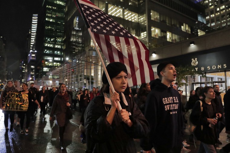 A protester carries an upside down American flag as she walks along Sixth Avenue while demonstrating against President-elect Donald Trump, Nov. 9, 2016, in New York. (Photo by Julie Jacobson/AP)