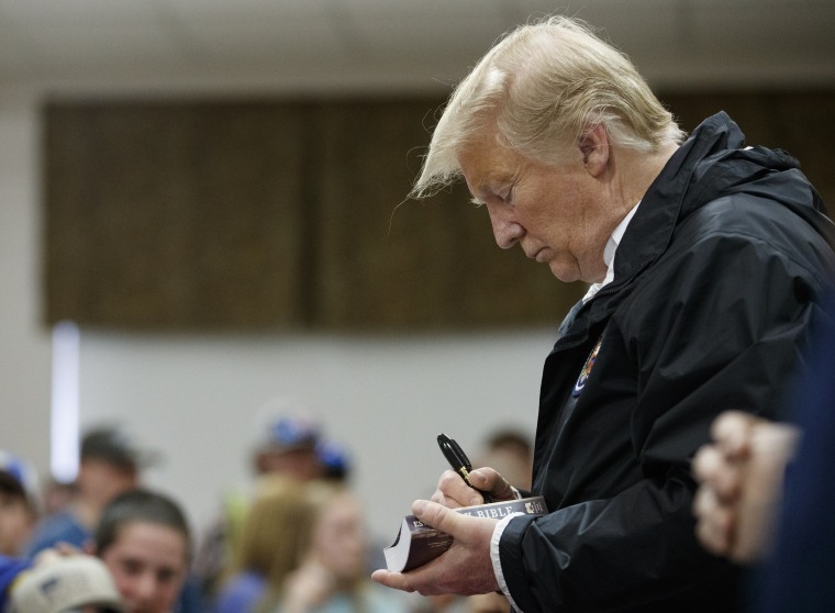 President Donald Trump signs a Bible as he greets people at Providence Baptist Church in Smiths Station, Ala., Friday, March 8, 2019, during a tour of areas where tornadoes killed 23 people in Lee County, Ala.