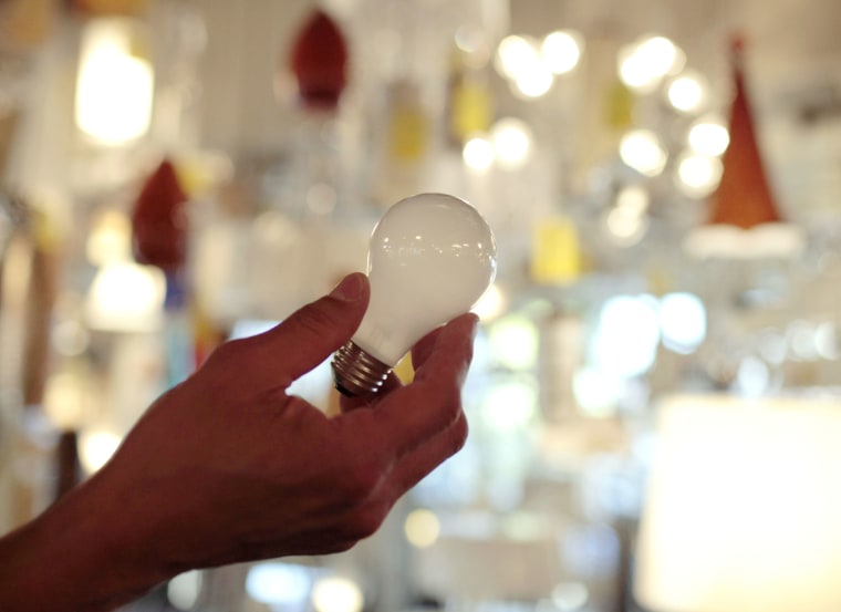 In this Jan. 21, 2011, file photo, Manager Nick Reynoza holds a 100-watt incandescent light bulb at Royal Lighting in Los Angeles.