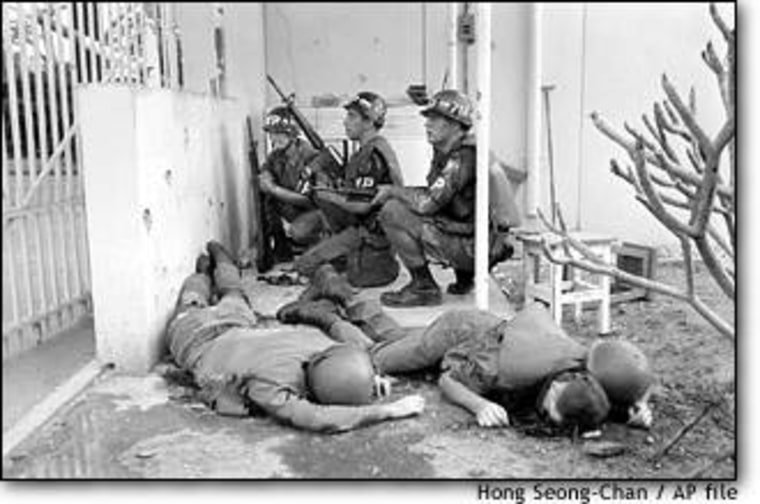 U.S. military police, dead colleagues at their side, take cover at the entrance to the U.S. Embassy in Saigon on the first day of the Tet Offensive, Jan. 31, 1968.