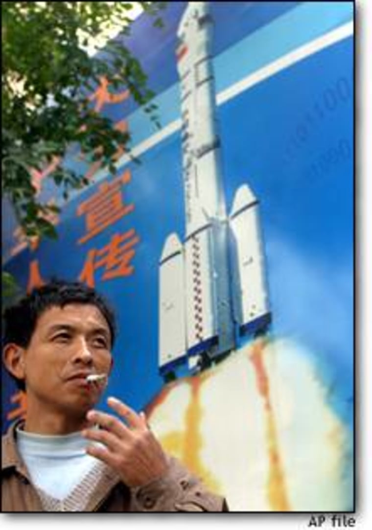 A Beijing resident passes a public information board advocating the learning of technical knowledge and showing the Long March rocket used in China's space program.