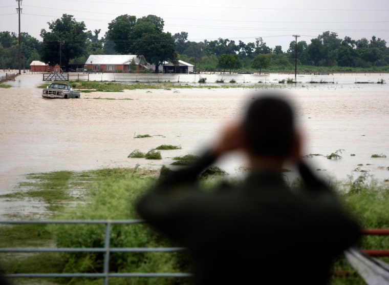 A Border Patrol agent looks for people needing assistance Saturday near D'Hanis, Texas, after heavy rains caused the Seco Creek to overflow its banks. flooding the town and closing U.S. Highway 90 in both directions.