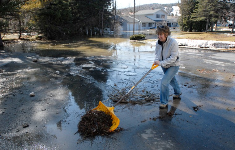 Christine Chasse cleans debris off her driveway as the water recedes in Fort Kent, Maine, on Thursday. A hastily made berm protected her home from the Fish River on one side while the town levee protected her home form the St. John River on other side.