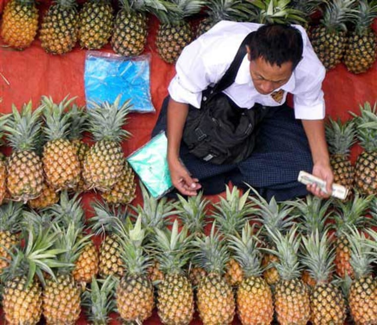 A man selling fresh pineapples waits for customers Saturday, July 5, 2008, in Yangon City, Myanmar. A variety of local cuisine as well as fruits and vegetables are sold on the city's sidewalks. Credit: AP Photo