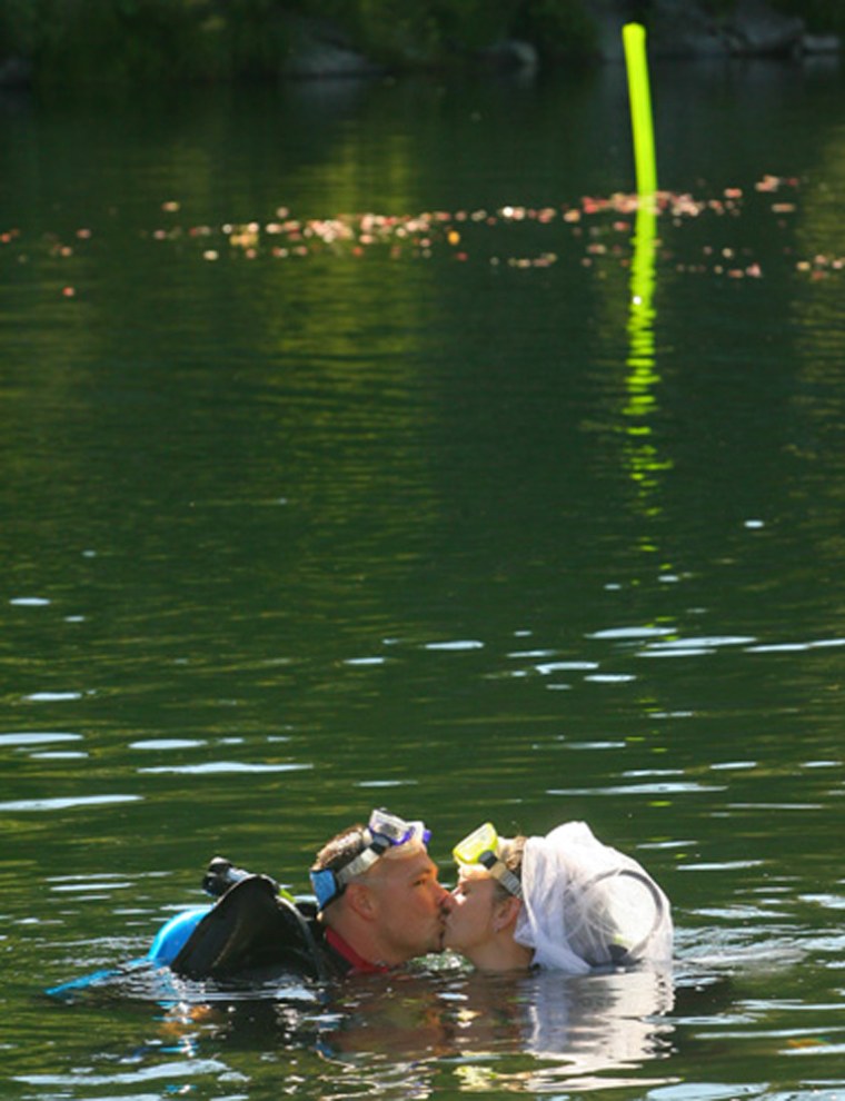JIM KROIS/Daily Courier
Brian and Christina Wilson kiss after their underwater wedding. The green marker behind them marks the place where they tied the knot 20 feet below the surface.