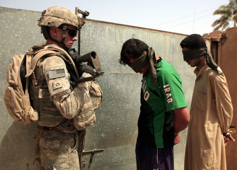 Image: A U.S. Army soldier stands guard near two suspected terrorists in Nahr al-Imam, Iraq