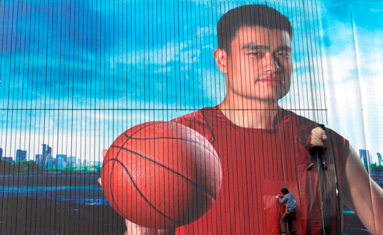 Workers paste an ad of Chinese NBA star Yao Ming on a billboard in Xiangfan in central China's Hubei province