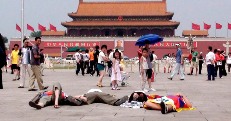 Image: foreign activists draped in Tibetan flags lying on the pavement at Tiananmen Square
