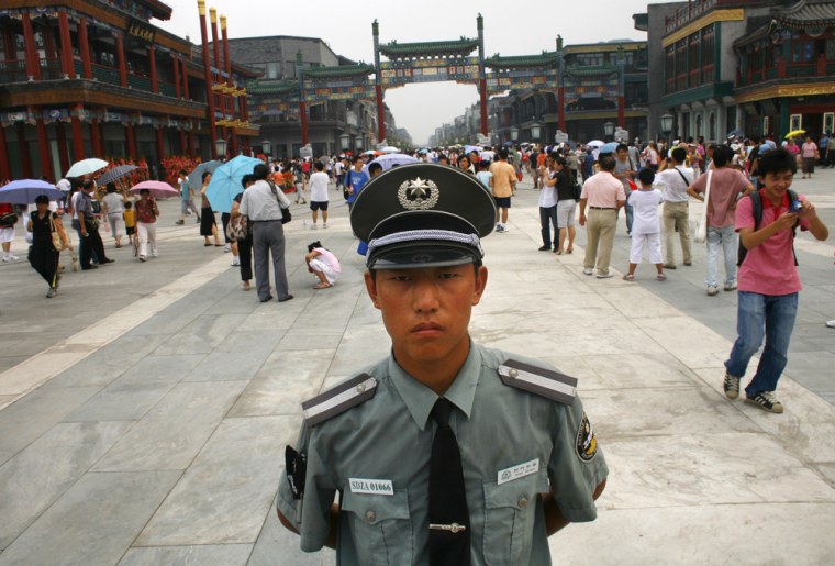 Image: Chinese police stand guard the entrance of the newly opened Qianmen shopping street