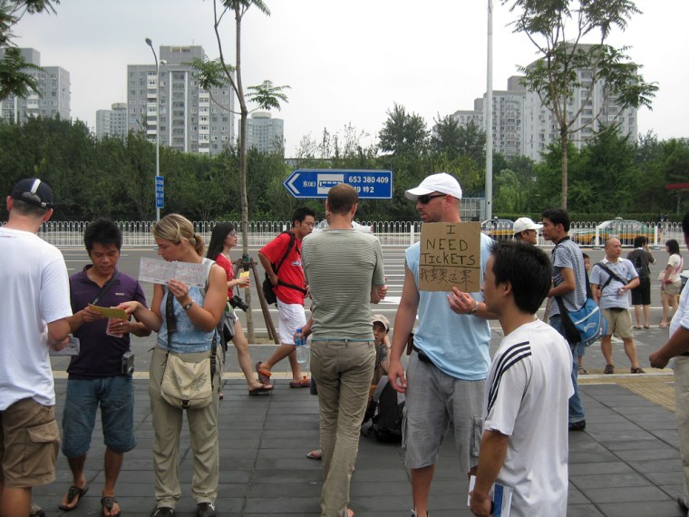 Image: Benny Daniel, holding the \"I need tickets\" sign, works the sidewalk outside the Beitucheng subway station