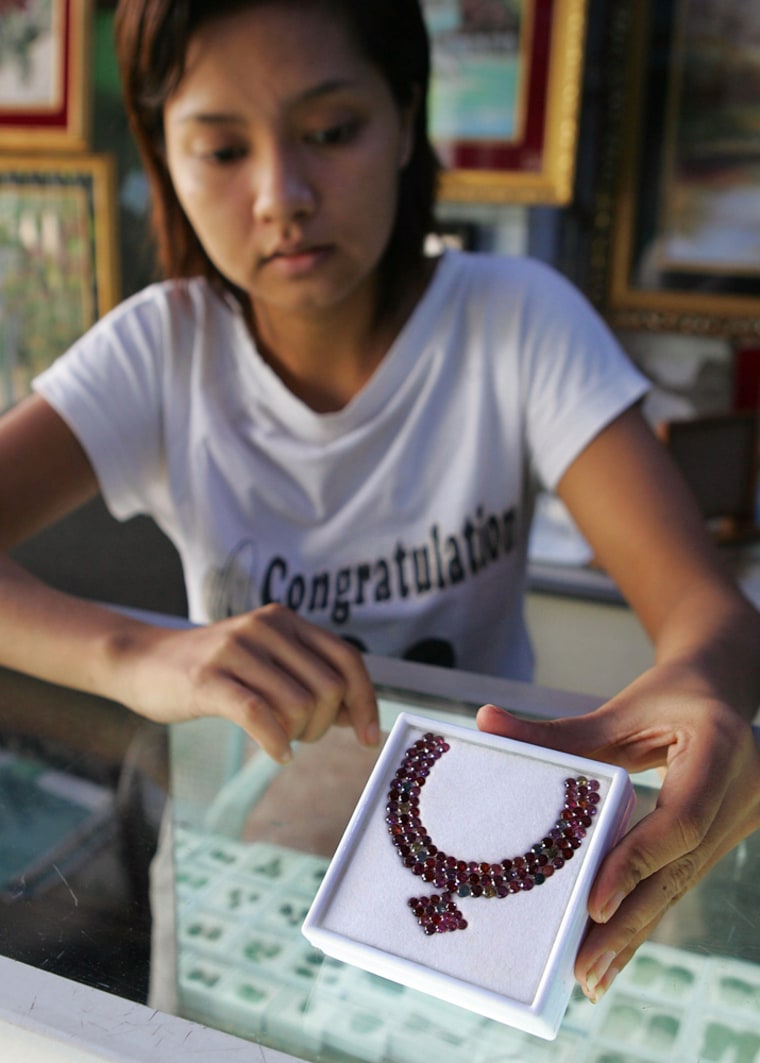 A salesclerk shows a necklace made from ruby and other precious stones in a souvenir shop Wednesday, July 23, 2008 in Yangon City, Myanmar. 