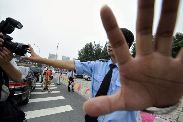 Image: A Chinese policeman stops photojournalists from taking pictures.