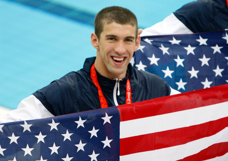 Image: Michael Phelps of the U.S. holds his national flag