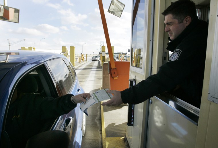 U.S. Customs officer Nick Ligerakis hands back a Michigan drivers license and information pamphlet to a driver arriving from Canada at the Ambassador Bridge in Detroit, Wednesday, Jan. 30.
