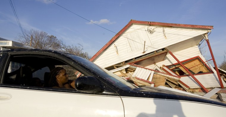 Image: A woman drives past a house destroyed by Hurricane Ike