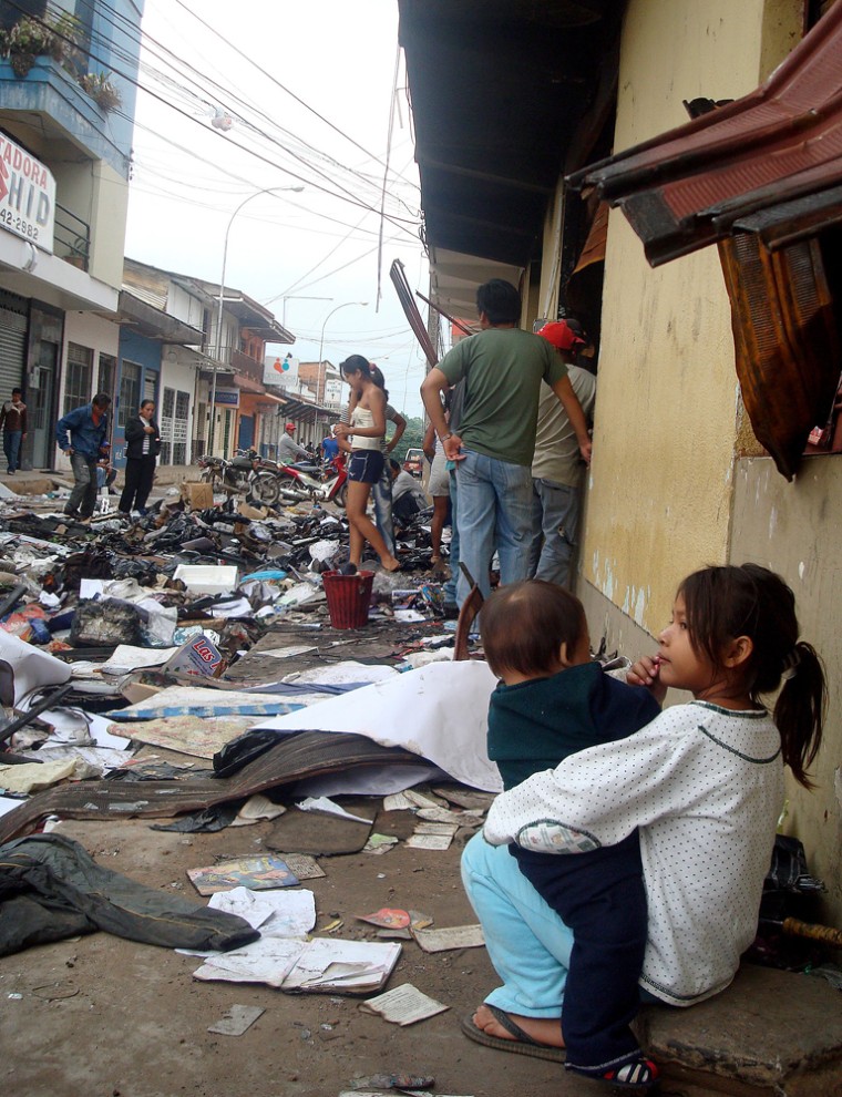 People survey damage on street where stores were looted by protesters in Pando province