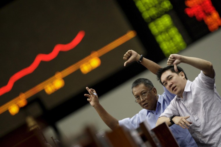 Image: Filipino traders display thumbs down signs in front of the Philippine Stock Exchange trading board