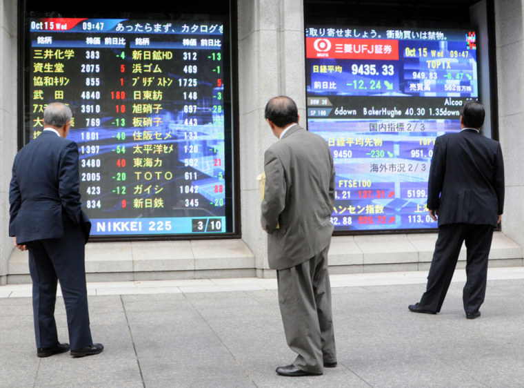 Image: Pedestrians take a look at stock indicators in Tokyo
