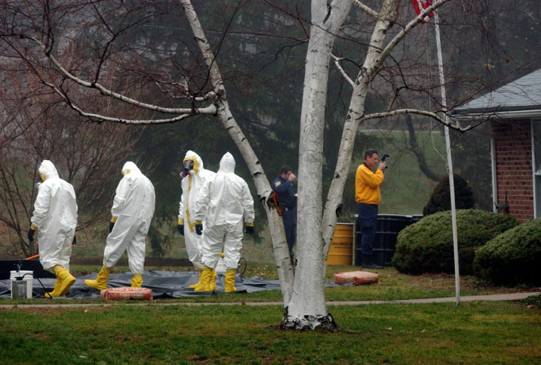 Image: In this Nov. 30, 2001 file photo, a decontamination crew dressed in hazmat suits stands together as an investigator takes photographs outside Ottilie Lundgren's home in Oxford, Conn.