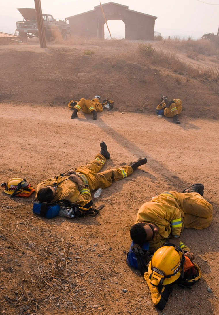 Firefighters sleep after protecting homes during Harris Ranch wildfire being fought in San Diego