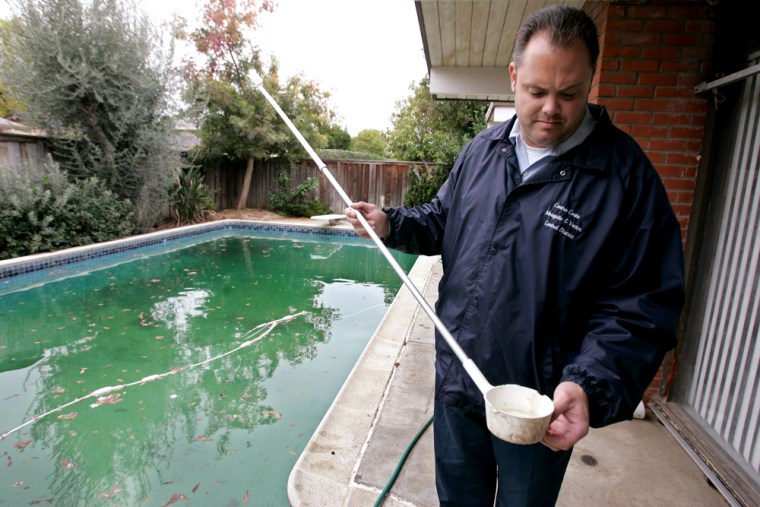 Contra Costa County public health worker Jeremy Tamargo looks at a water sample for mosquitoes from this dirty pool at an empty foreclosed home in Concord, Calif. Dank, brown and fetid, the backyard pool has morphed from a once-sparkling turquoise to a breeding ground for mosquitos and worse.