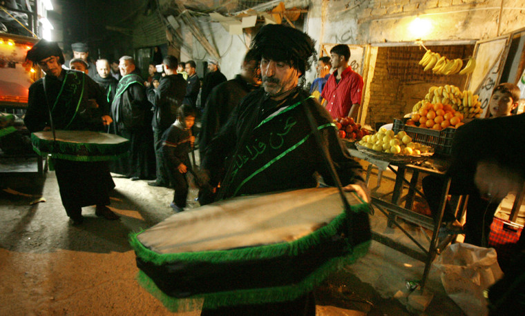 Image: Iraqi men beat on drums at the fruit market in the Kazimiyah neighborhood in Baghdad