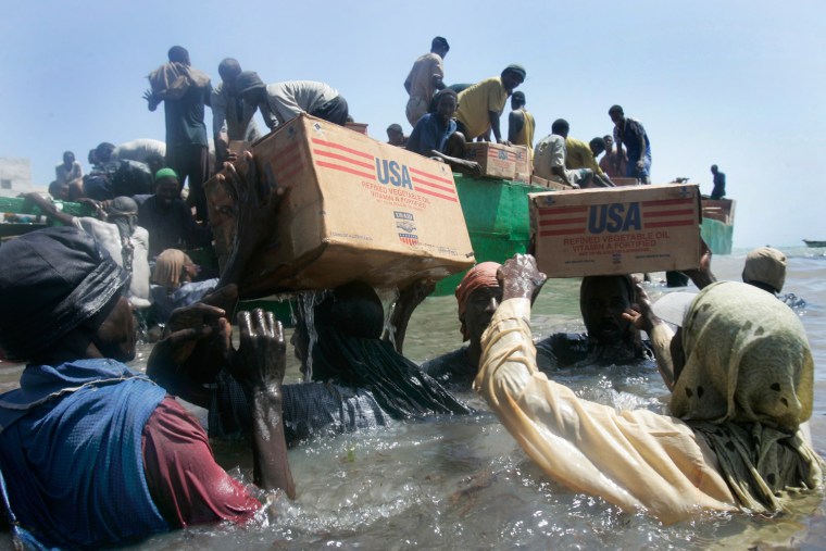 Image: Somali men carry food aid from a barge to shore