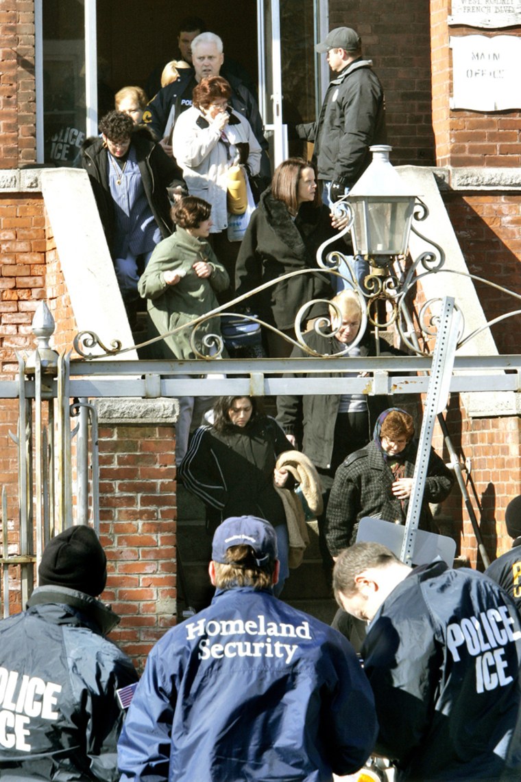 Employees are escorted out after an early-morning raid by federal immigration officials at the Michael Bianco Inc. textile plant in New Bedford, Mass., in March 2007.  