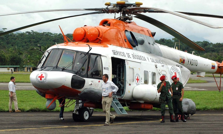 Image: Officials and Venezuelan soldiers stand near an army helicopter with stickers of the Red Cross at the Santo Domingo airport