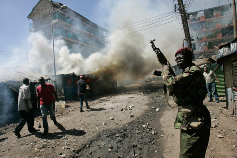 Image: A police officer attempts to secure an area in front off burning buildings in Nairobi, Kenya.