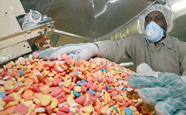 Image:  Fredo Deneus makes adjustments to the assembly line of Sweetheart candies before they are packaged