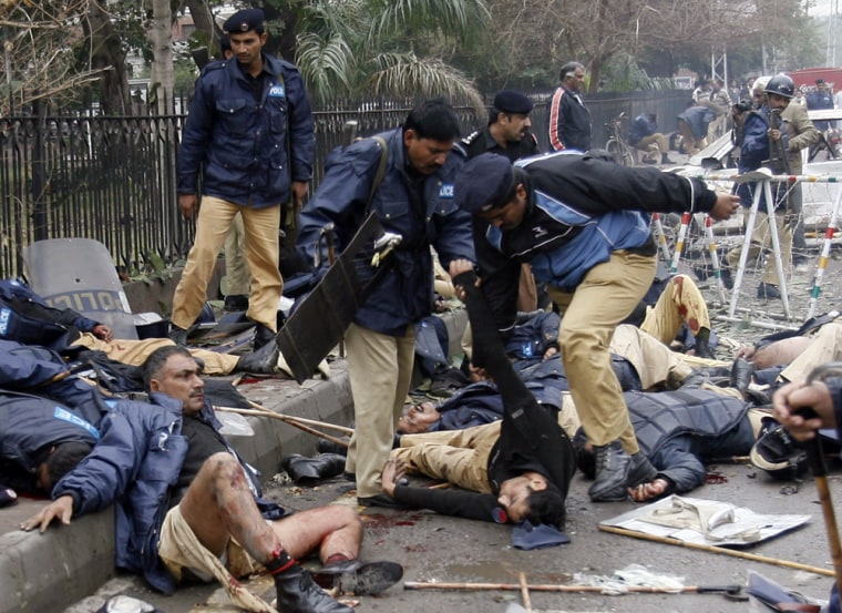 Police help their colleagues injured in a suicide bombing outside a court in the centre of the Pakistani city of Lahore