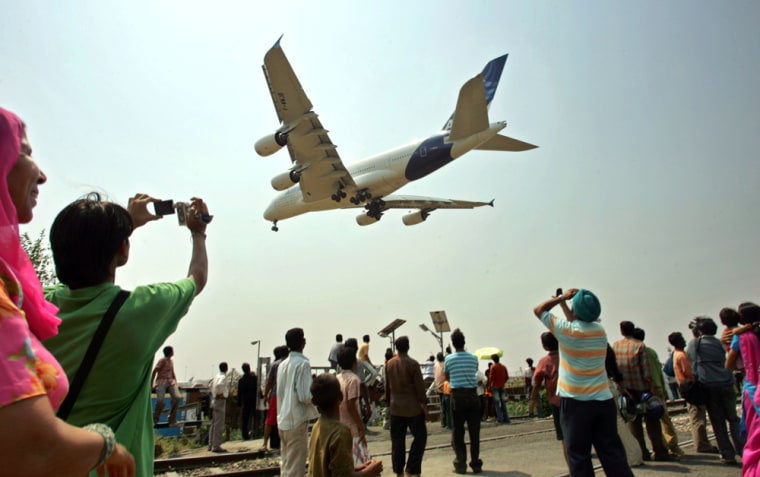 Image: People look on as an Airbus A380 prepares to land at the Indira Gandhi International Airport in New Delhi, India