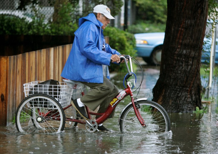 A man rides his bike through a flooded street in Palo Alto, Calif., during a rain storm on Friday. Streets flooded, hillsides slipped and commuters cursed during powerful rain and snow storms that lashed Southern California.