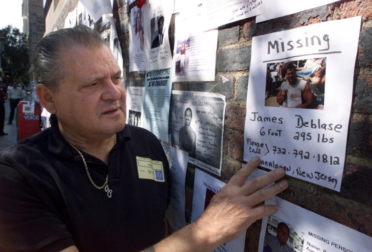 Image: James Deblase looks at a photo of his son posted on the wall outside the 69th Regiment Armory in New York after the Sept. 11 attacks.