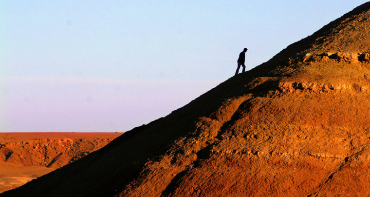 Image: A tourist climbs to the top of Ait Ben Haddou fortress near Ourzazate, Morocco