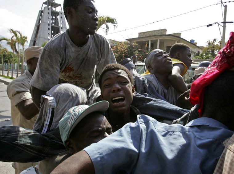 Image: Men are forced into a police truck after being detained for allegedly looting near the presidential palace in Port-au-Prince.
