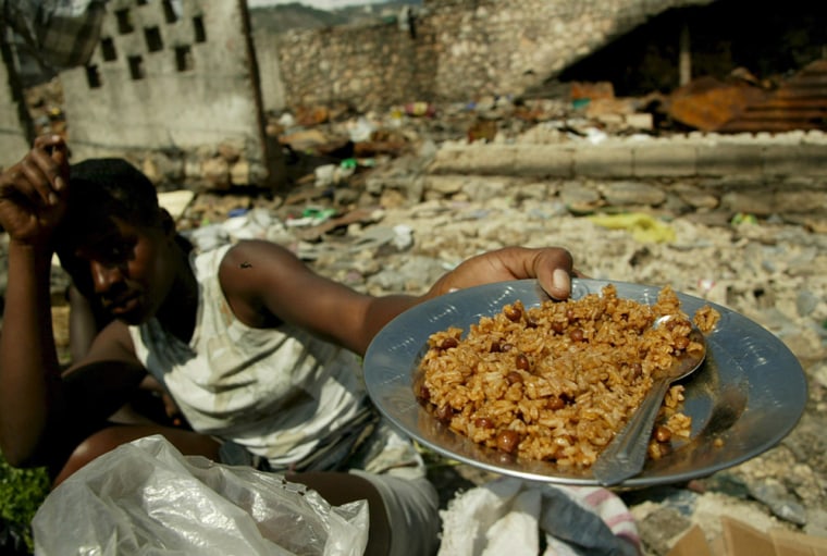 Image: A Haitian woman shows a dish with rice, main ingredient of the Haitian diet,