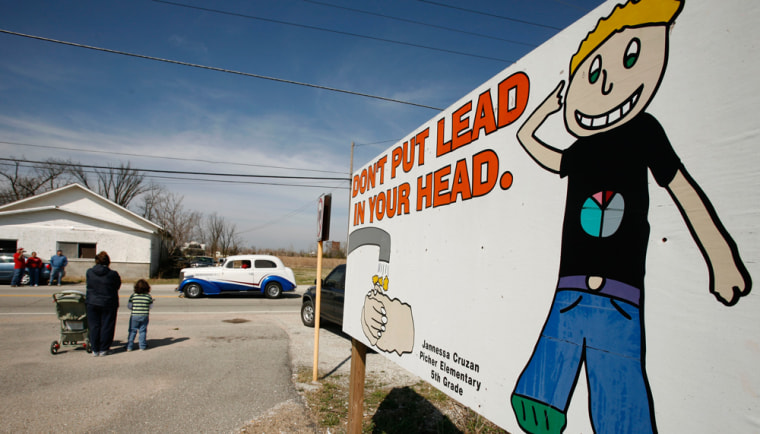 A small parade celebrating the 90th anniversary of Picher, Okla. passes a sign warning of lead hazards in the town, Saturday, April 6, 2008. The town's population has dwindled to a fraction of it's former size as people gradually move away from the Tar Creek Superfund site left from years of lead and zinc mining. (AP Photo/Charlie Riedel)