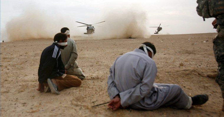 **FILE** In this Nov. 16, 2007 file photo, a U.S. soldier of 3rd Brigade combat team of the 101st Airborne Division guards detainees, suspected of insurgents activities, while waiting for helicopters to land during an operation Marne Courageous in the village of Owesap, 20 kilometers (12 miles) south of Baghdad, Iraq. The amnesty rulings could offer an early exit for many of the 27,000 prisoners in Iraqi hands. They also could wipe the slate for hundreds of the roughly 22,000 detainees held by the U.S. military. (AP Photo/Petr David Josek)