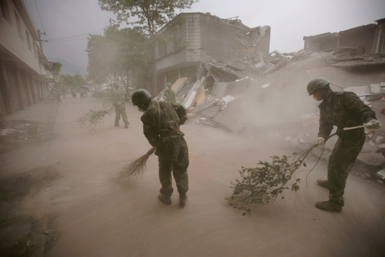 Soldiers clean broken glass from a road in Hanwang town Wednesday next to buildings destroyed by last week's earthquake in China.