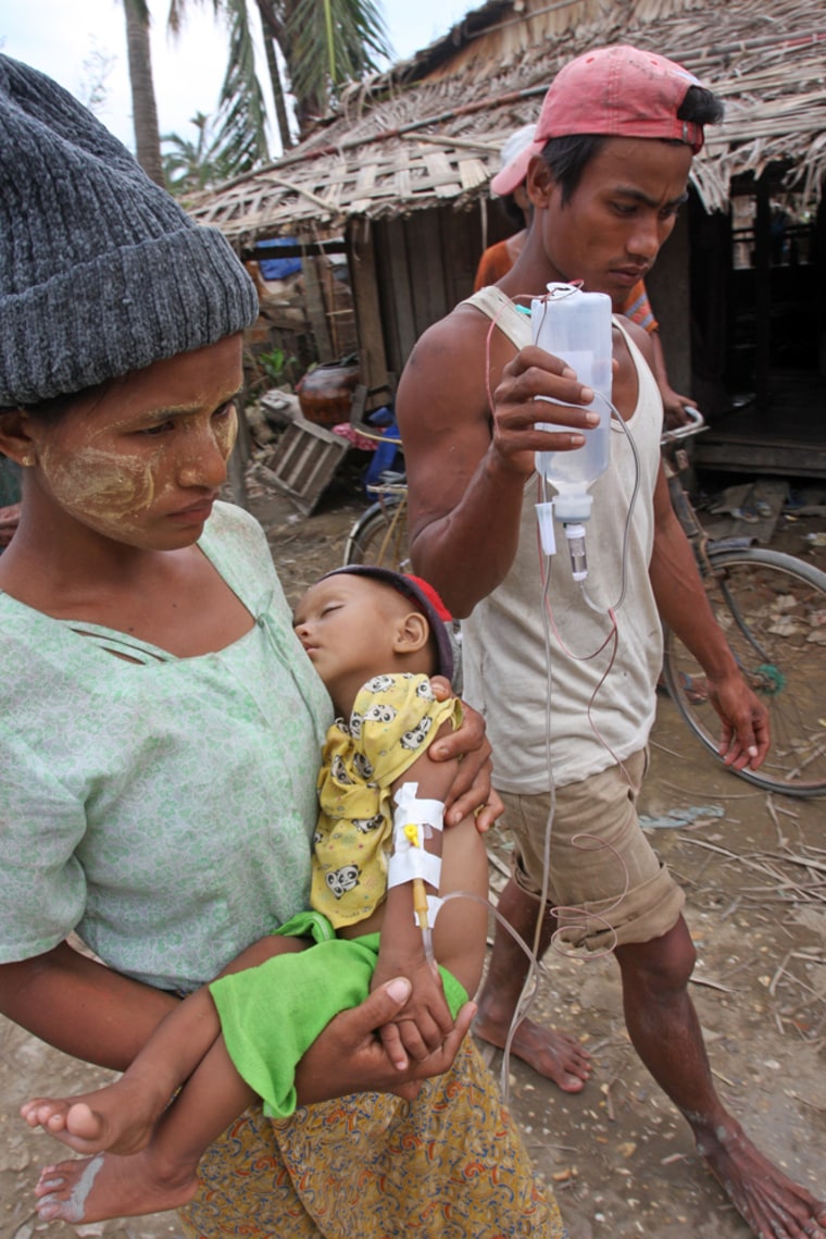 Parents carry their child, who is receiving medical treatment near the Irrawaddy Delta town of Labutta on Saturday. Labutta is about 200 miles from Myanmar's largest city, Yangon. 