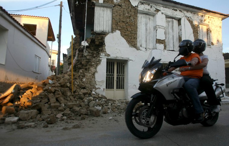 A couple passes by a destroyed house in Kato Ahagia, Greece, on Sunday, June 8 after a strong earthquake killed at least two people, and injured more than 100 others.