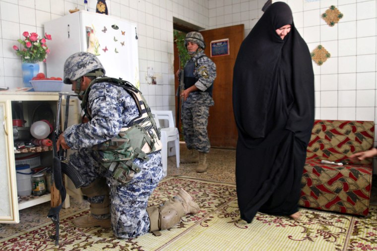 Image: An Iraqi woman stands in her kitchen