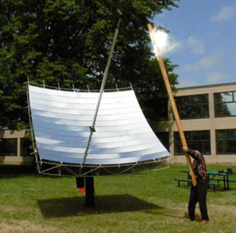 Inventor Doug Wood demonstrates the solar dish's power by using it to set fire to a board held at the focal point. Credit: David Chandler